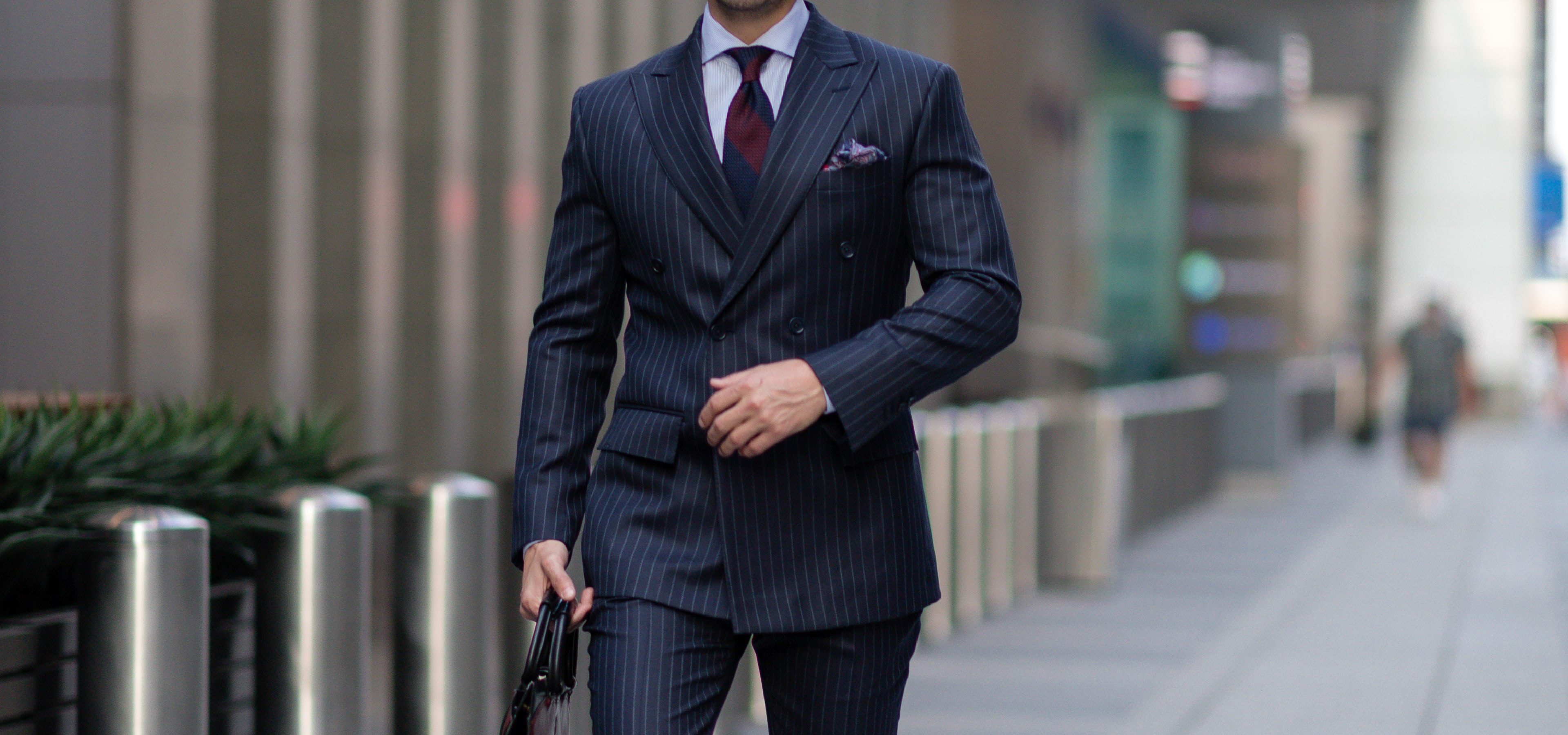 A man wearing a midnight blue pin stripe custom King & Bay business suit