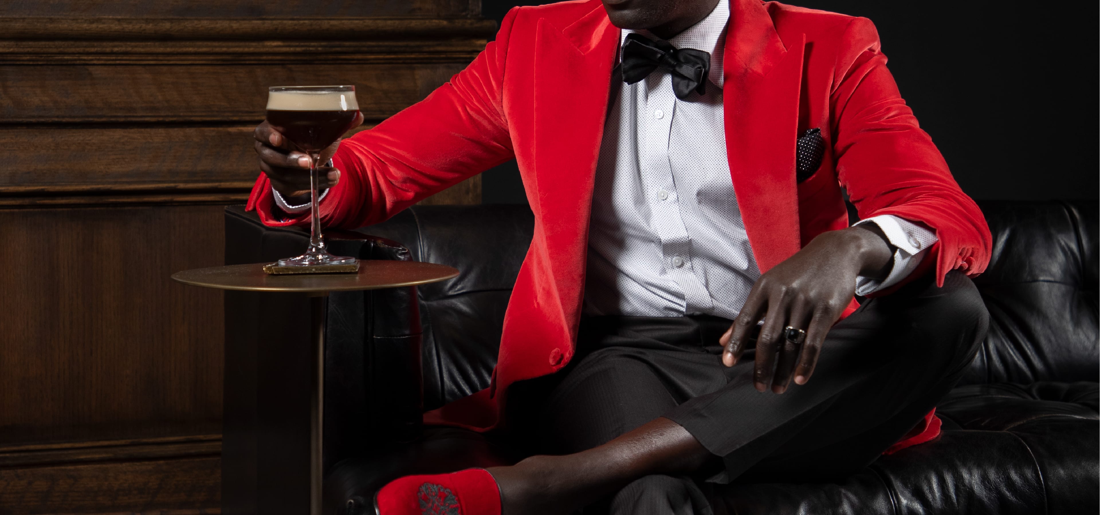 A man wearing a custom red velvet jacket drinking a King & Bay espresso martini